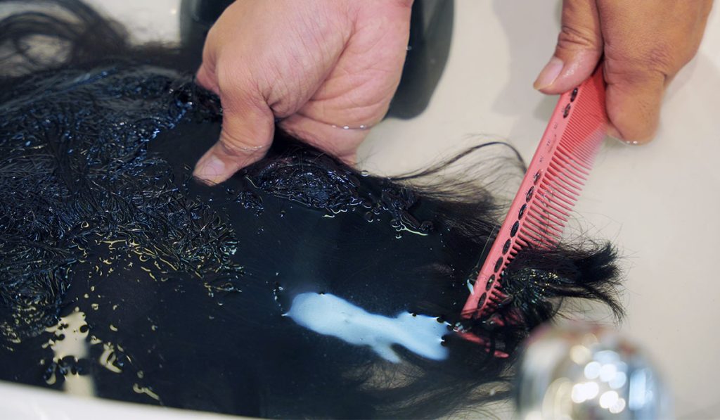 Washing a hair system in the water and detangling at the same time