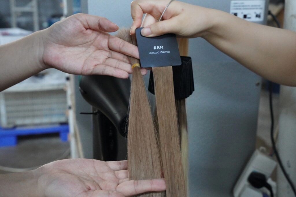 NEWTIMES HAIR technician compares dried #8N Toasted Walnut hair extensions with the approved color standard after dyeing.